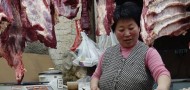 A butcher processes meat at a shop in Beijing